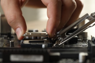 Man installing computer chip onto motherboard at table, closeup