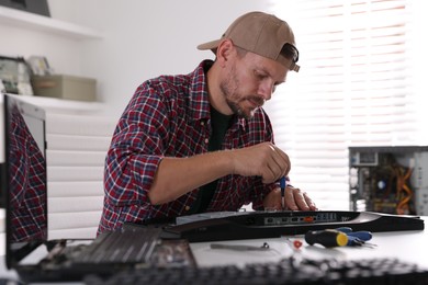 Man fixing computer monitor at white table