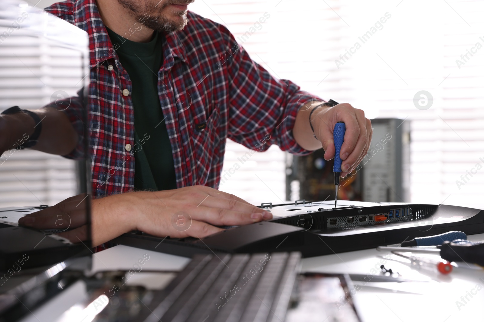 Photo of Man fixing computer monitor at white table, closeup