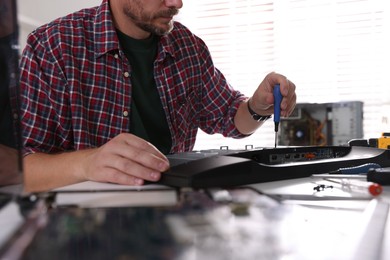 Man fixing computer monitor at white table, closeup