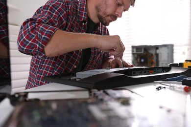 Man fixing computer monitor at white table, closeup