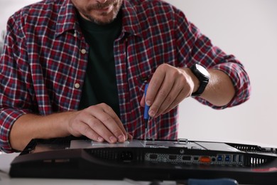 Man fixing computer monitor at white table, closeup