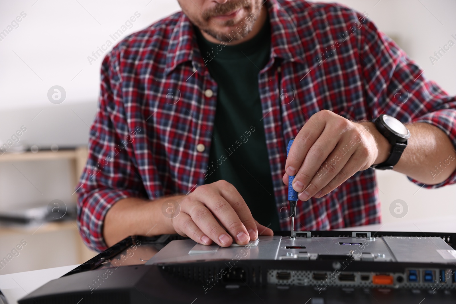 Photo of Man fixing computer monitor at white table, closeup