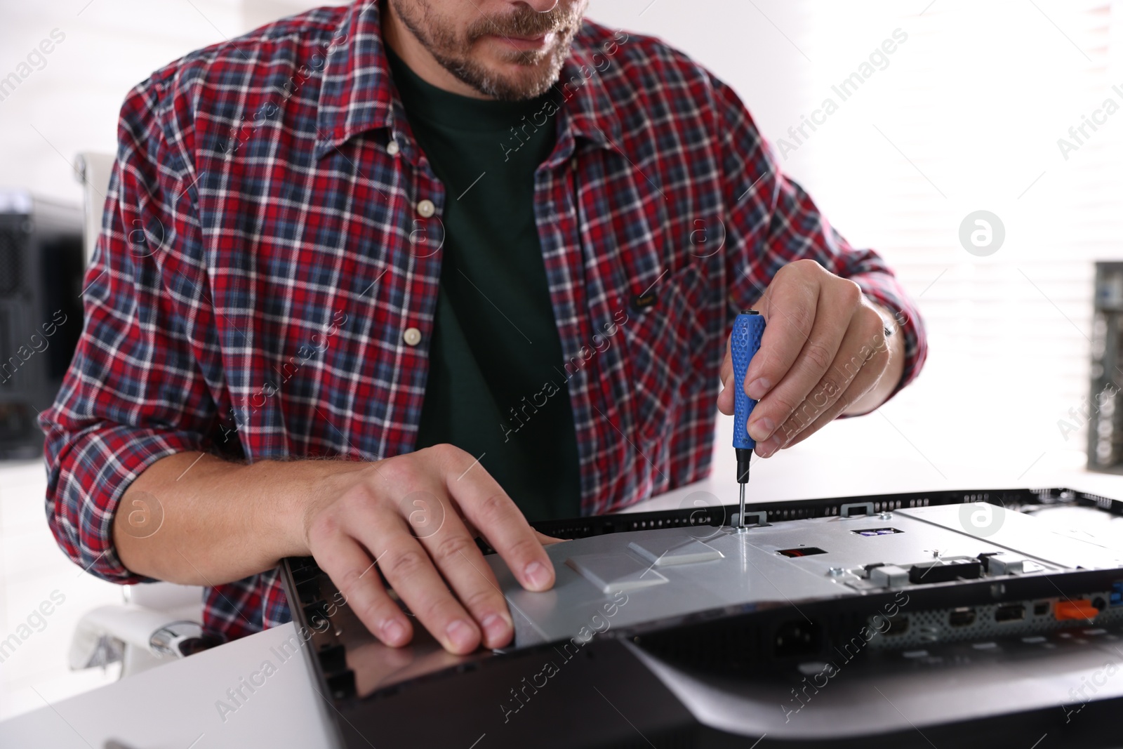 Photo of Man fixing computer monitor at white table, closeup