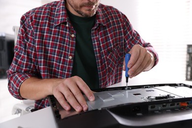 Man fixing computer monitor at white table, closeup