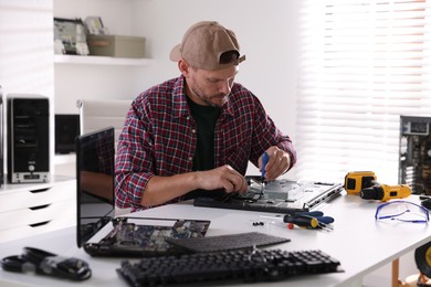 Photo of Man fixing computer monitor at white table