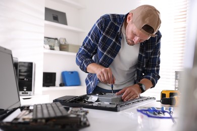 Photo of Man fixing computer monitor at white table