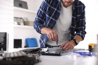 Photo of Man fixing computer monitor at white table, closeup