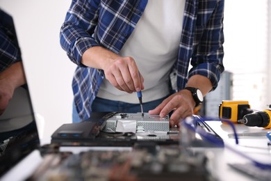 Man fixing computer monitor at white table, closeup