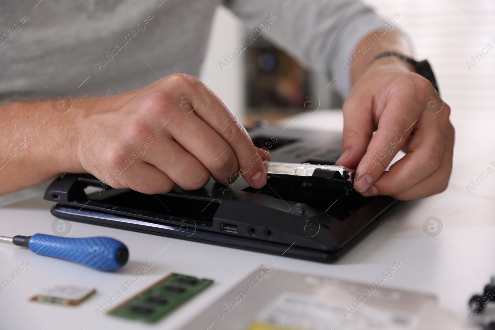 Photo of Man fixing old laptop at white table, closeup