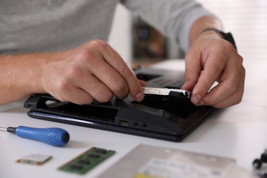 Man fixing old laptop at white table, closeup