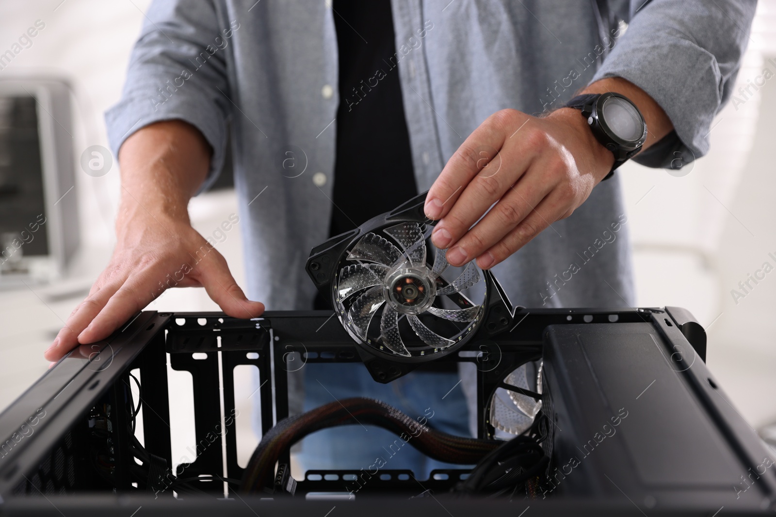 Photo of Man installing fan into computer at table, closeup