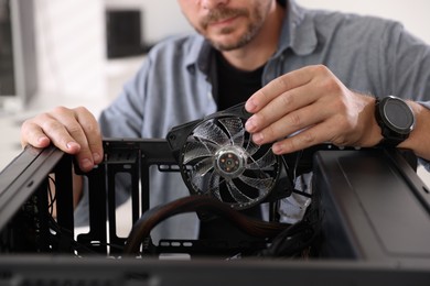 Man installing fan into computer at table, closeup