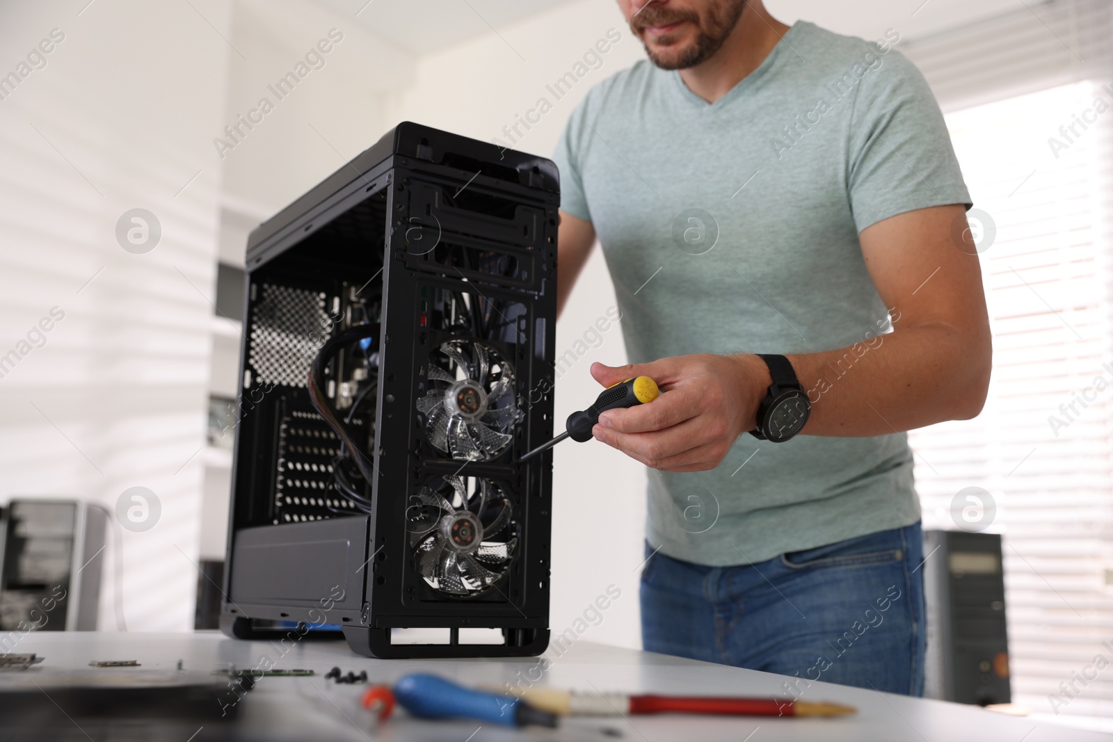 Photo of Man assembling new computer at white table, closeup