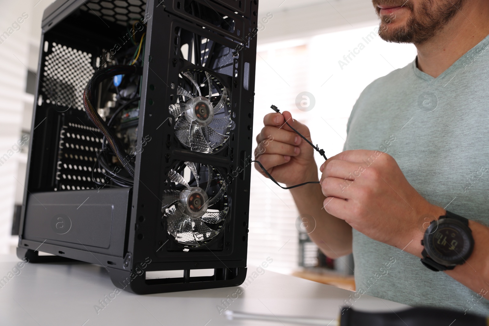 Photo of Man assembling new computer at white table, closeup