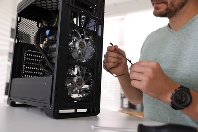 Photo of Man assembling new computer at white table, closeup