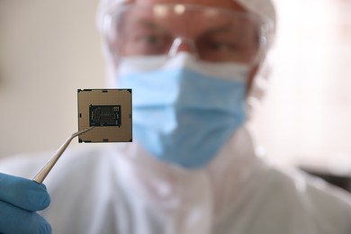 Photo of Man in mask holding computer chip on blurred background, selective focus