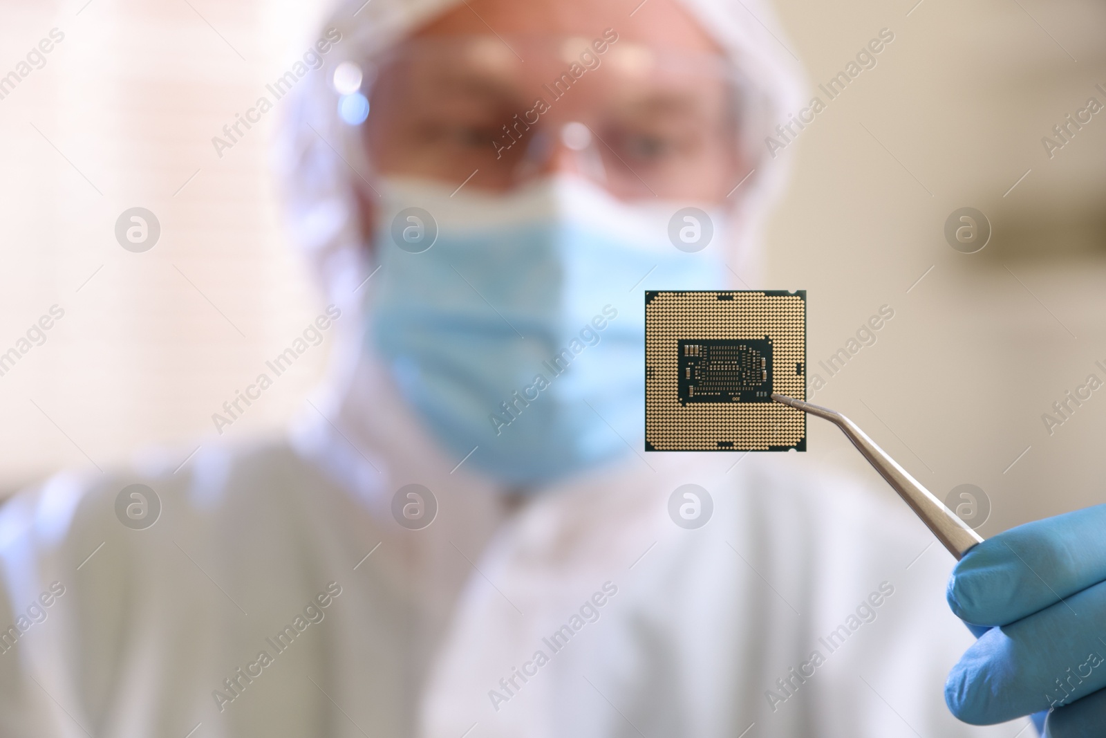 Photo of Man in mask holding computer chip on blurred background, selective focus