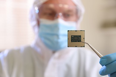 Photo of Man in mask holding computer chip on blurred background, selective focus