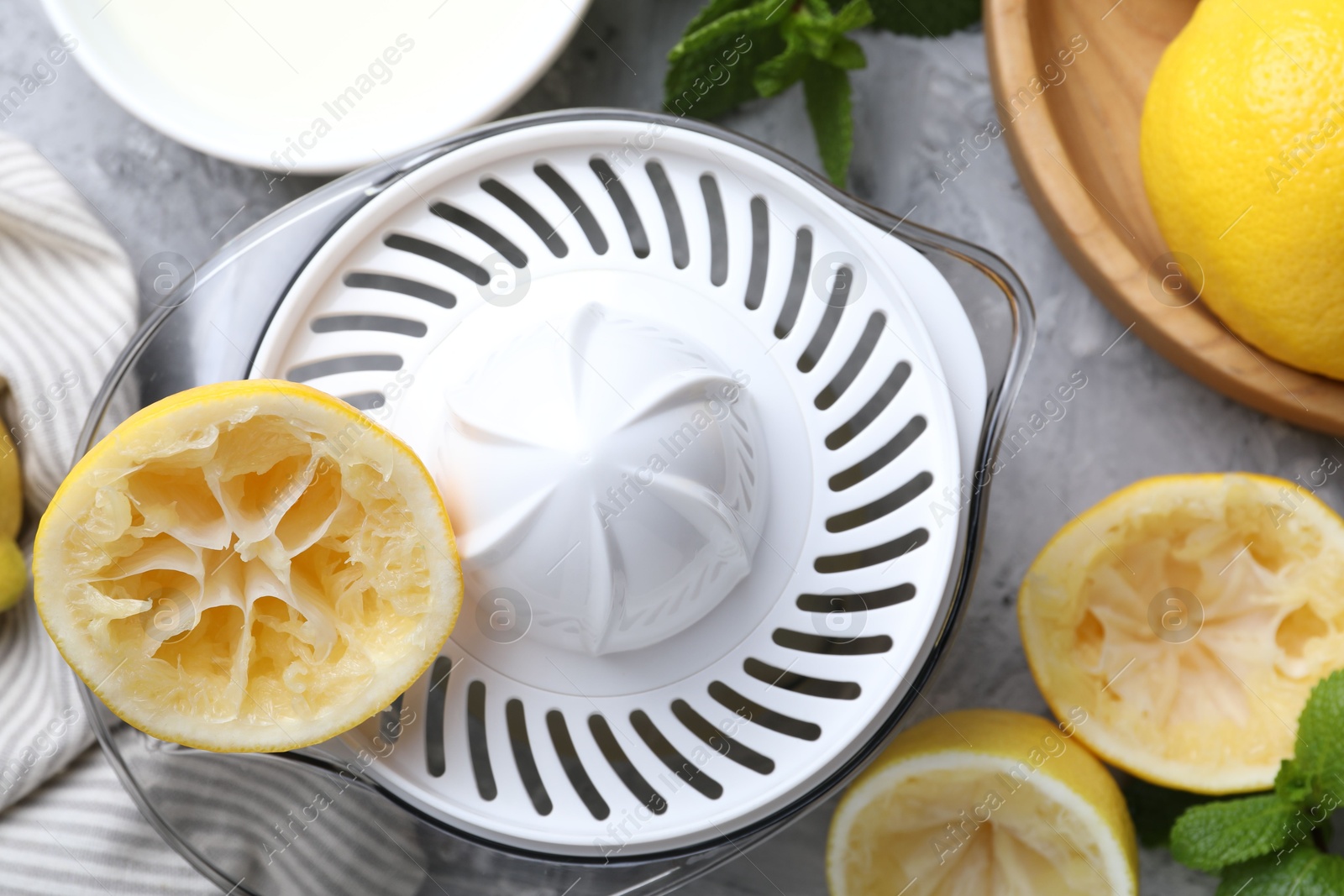 Photo of Juicer, lemons and mint on grey table, top view