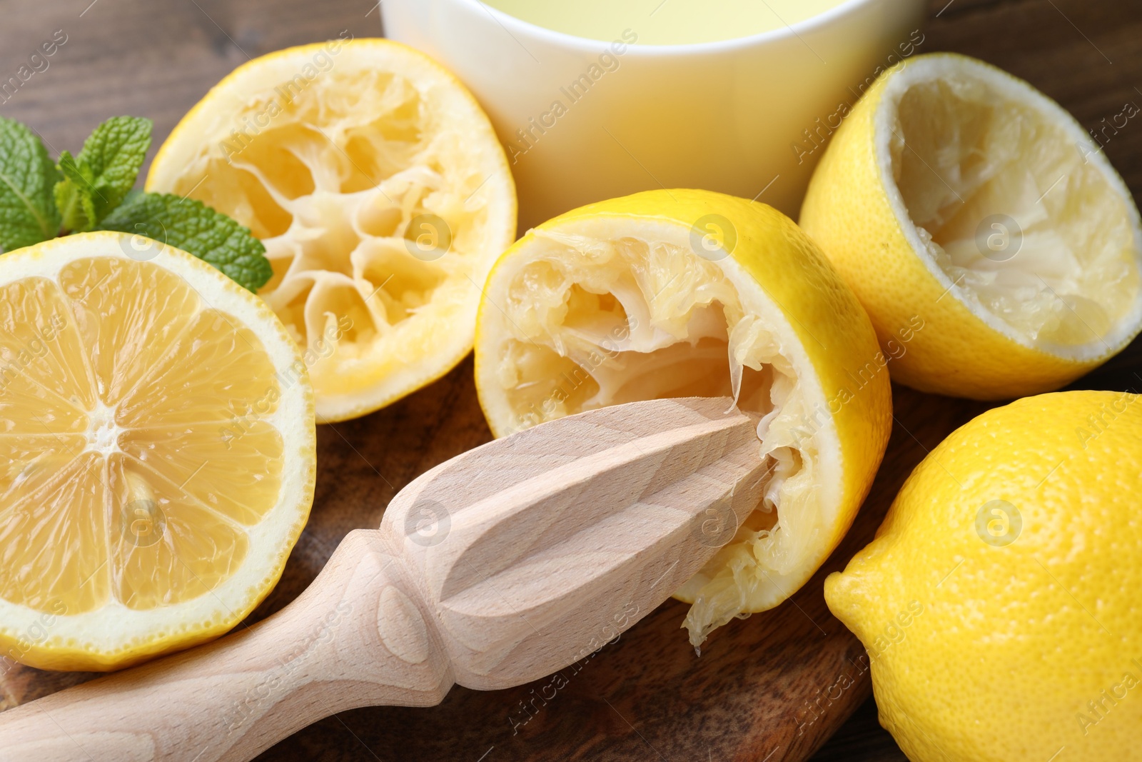 Photo of Wooden squeezer, lemons and mint on table, closeup