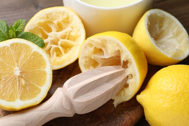 Photo of Wooden squeezer, lemons and mint on table, closeup