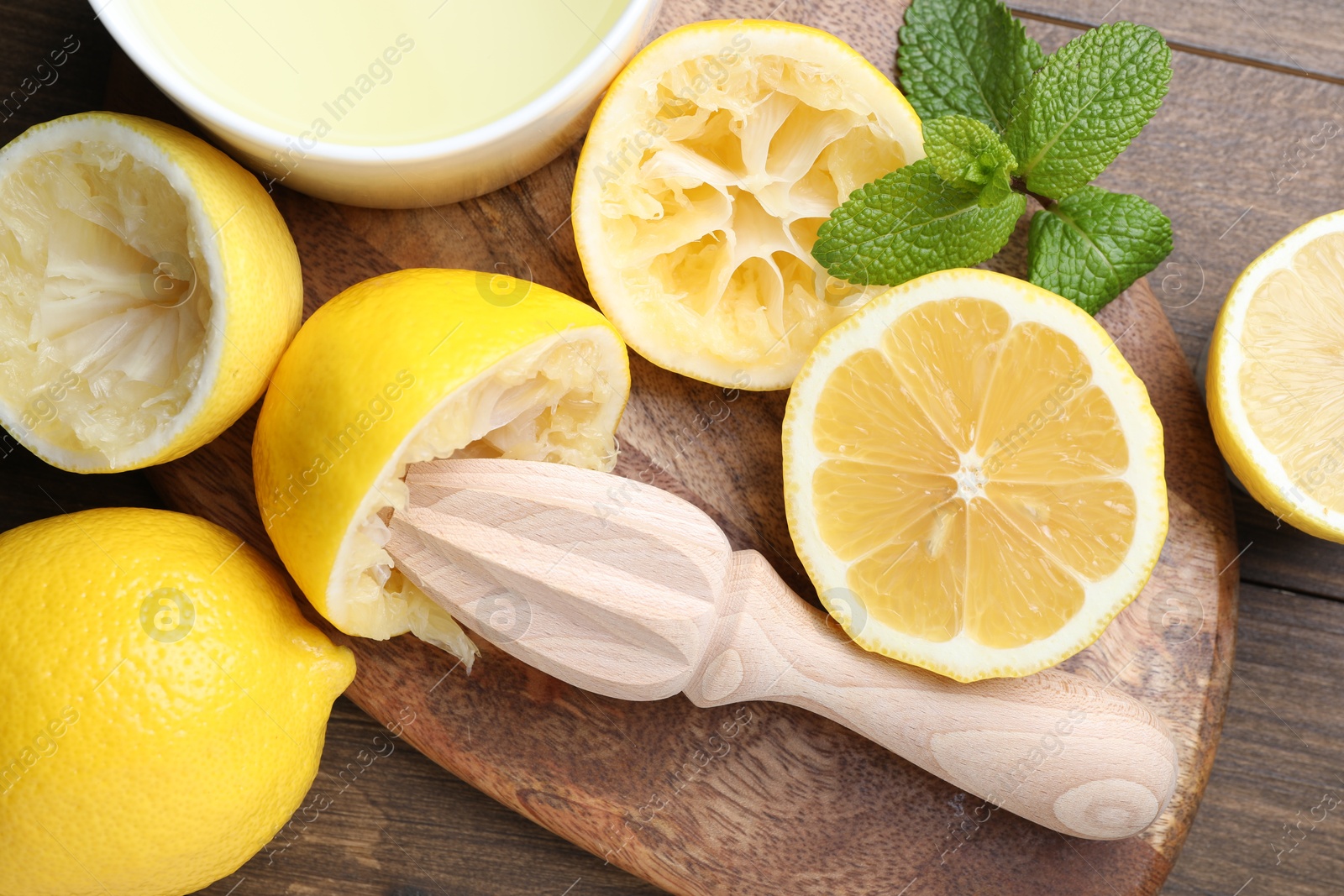 Photo of Squeezer, lemons, mint and juice on wooden table, top view