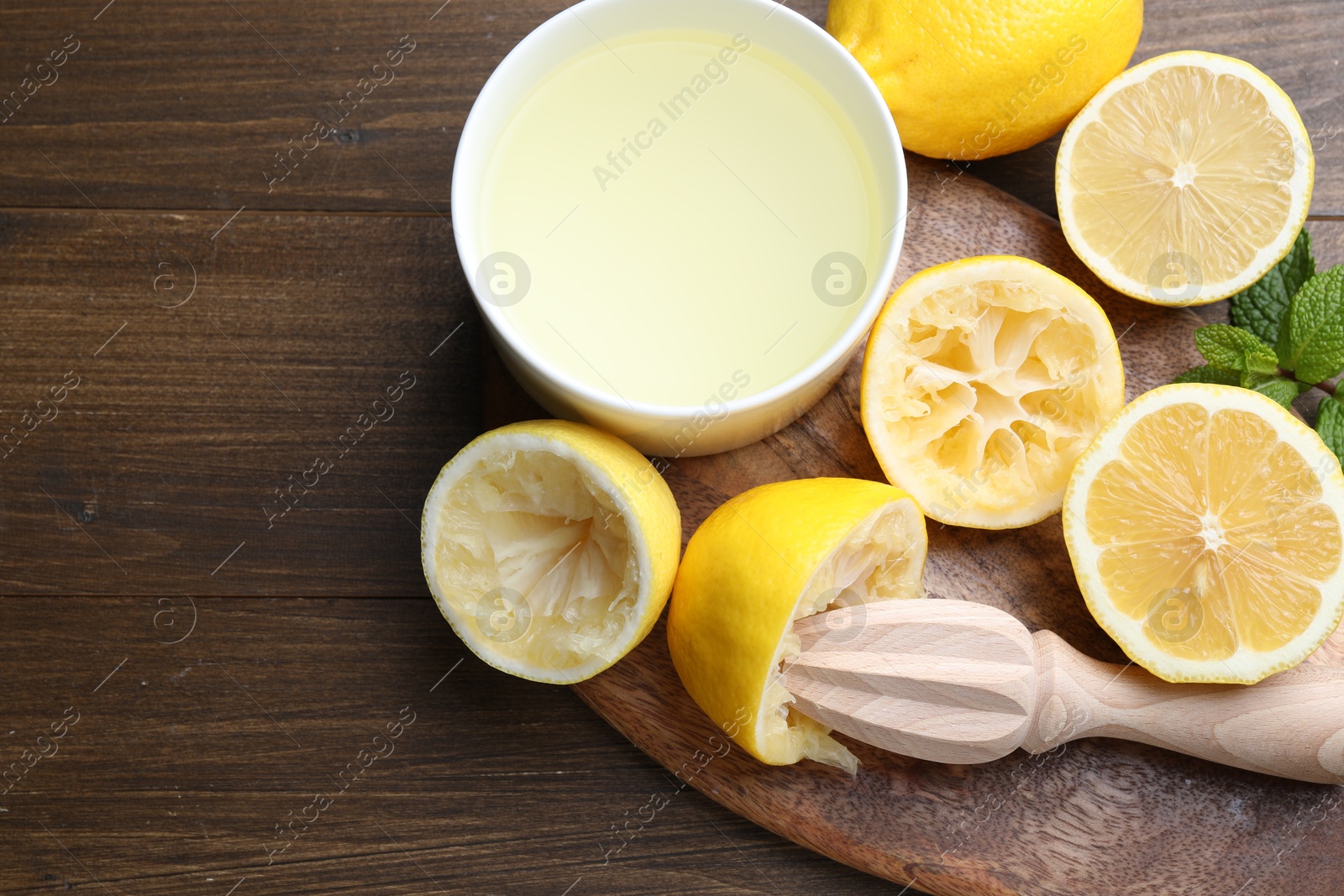 Photo of Squeezer, lemons, mint and juice on wooden table, top view. Space for text