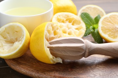 Photo of Wooden squeezer, lemons, mint and juice on table, closeup