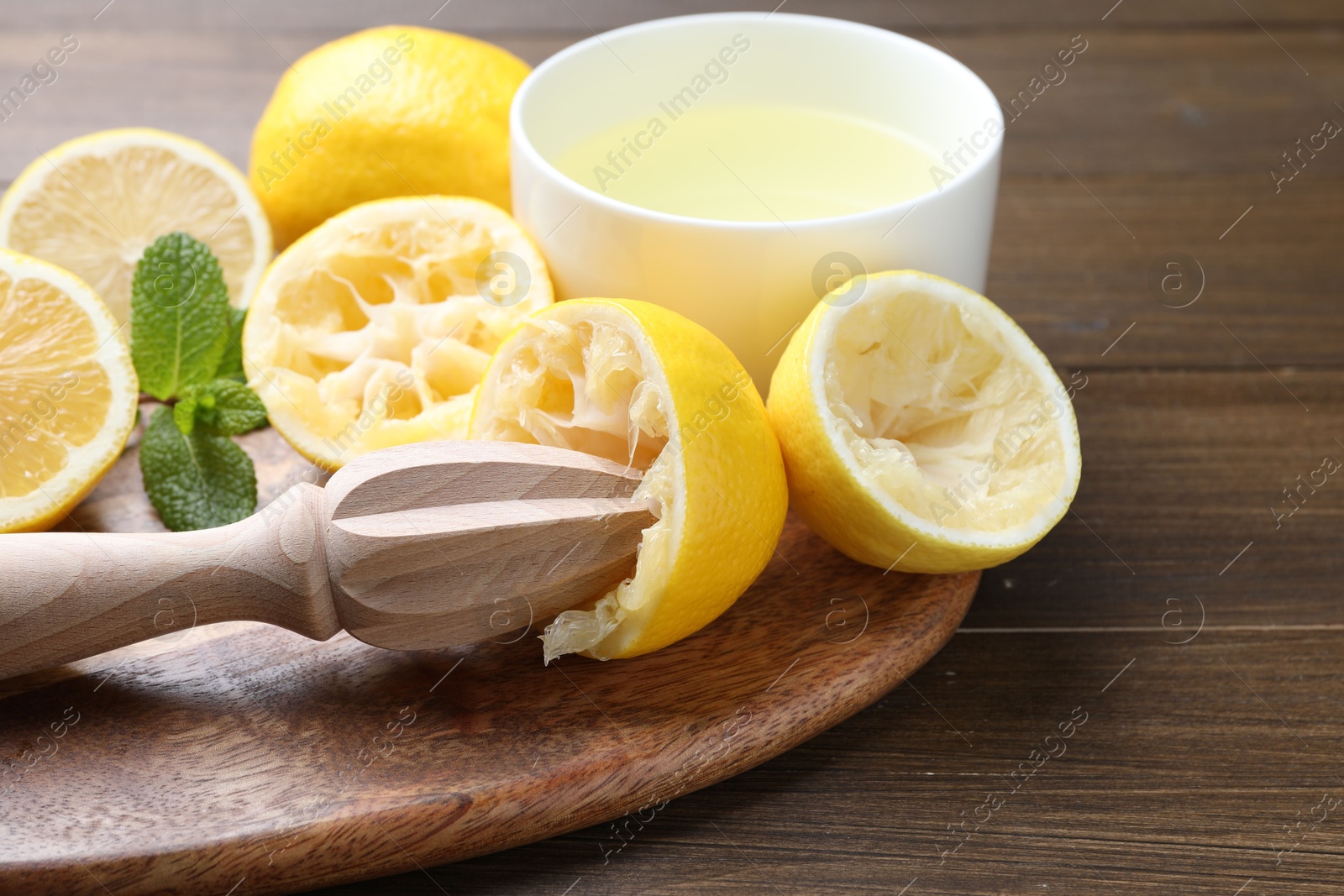 Photo of Squeezer, lemons, mint and juice on wooden table, closeup