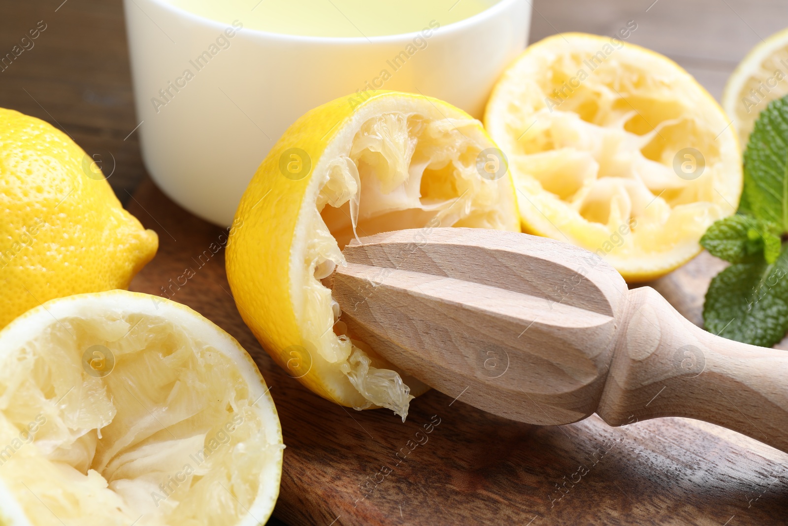 Photo of Squeezer, lemons and mint on wooden table, closeup