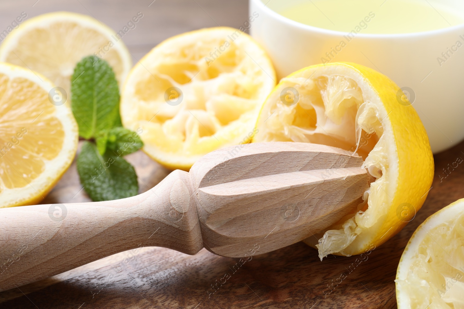 Photo of Squeezer, lemons and mint on wooden table, closeup