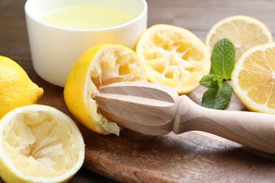 Photo of Wooden squeezer, lemons, mint and juice on table, closeup