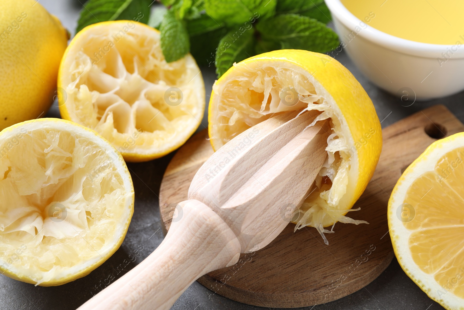 Photo of Wooden squeezer, lemons and mint on grey table, closeup