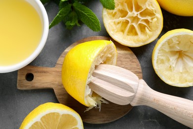 Photo of Wooden squeezer, lemons, juice and mint on grey table, top view