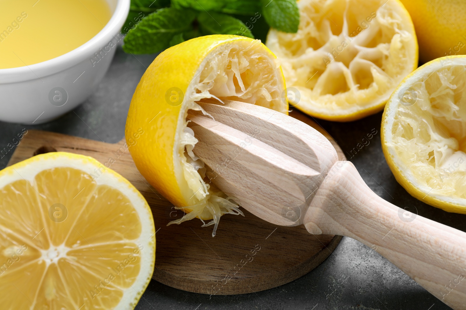 Photo of Wooden squeezer, lemons and mint on grey table, closeup