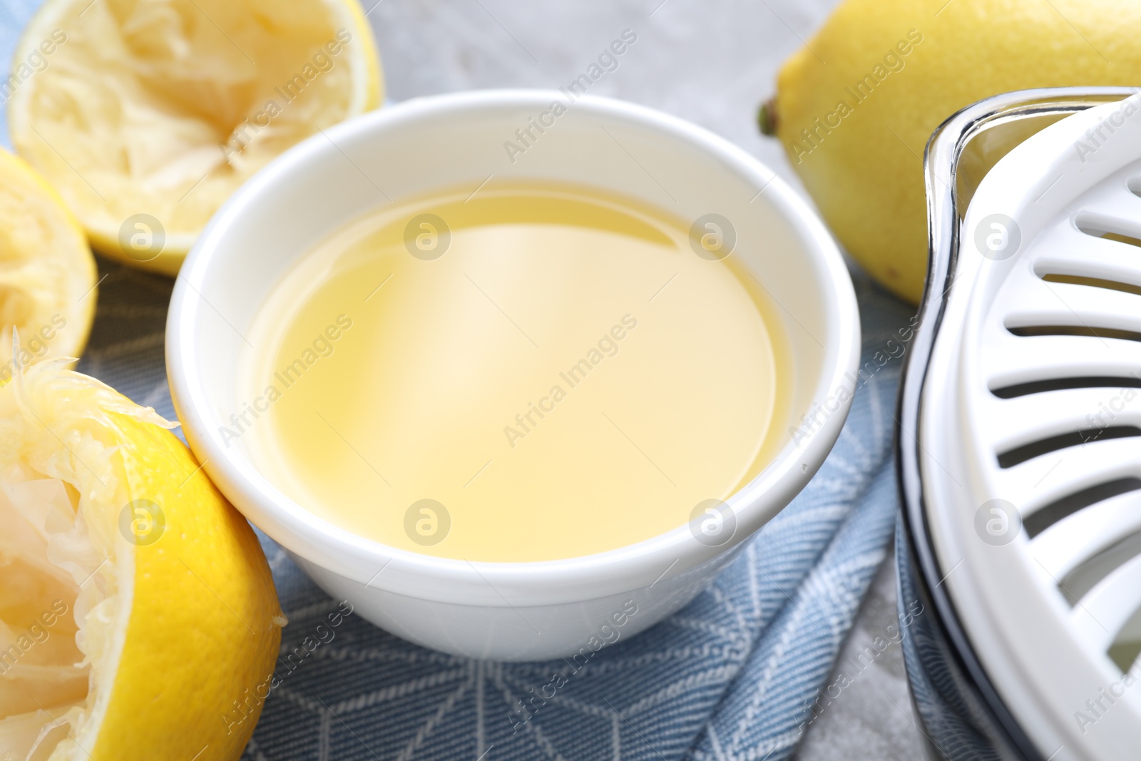 Photo of Fresh lemon juice in bowl and fruits on table, closeup