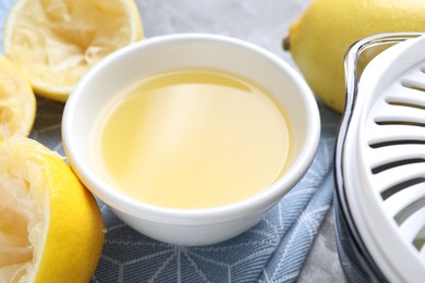 Photo of Fresh lemon juice in bowl and fruits on table, closeup