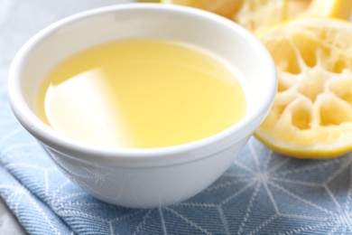 Photo of Fresh lemon juice in bowl and fruit on table, closeup