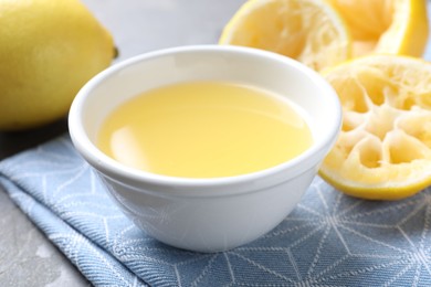 Photo of Fresh lemon juice in bowl and fruits on table, closeup