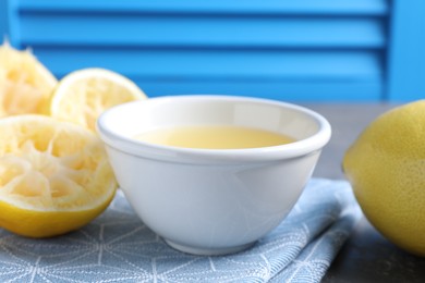 Photo of Fresh lemon juice in bowl and fruits on table, closeup