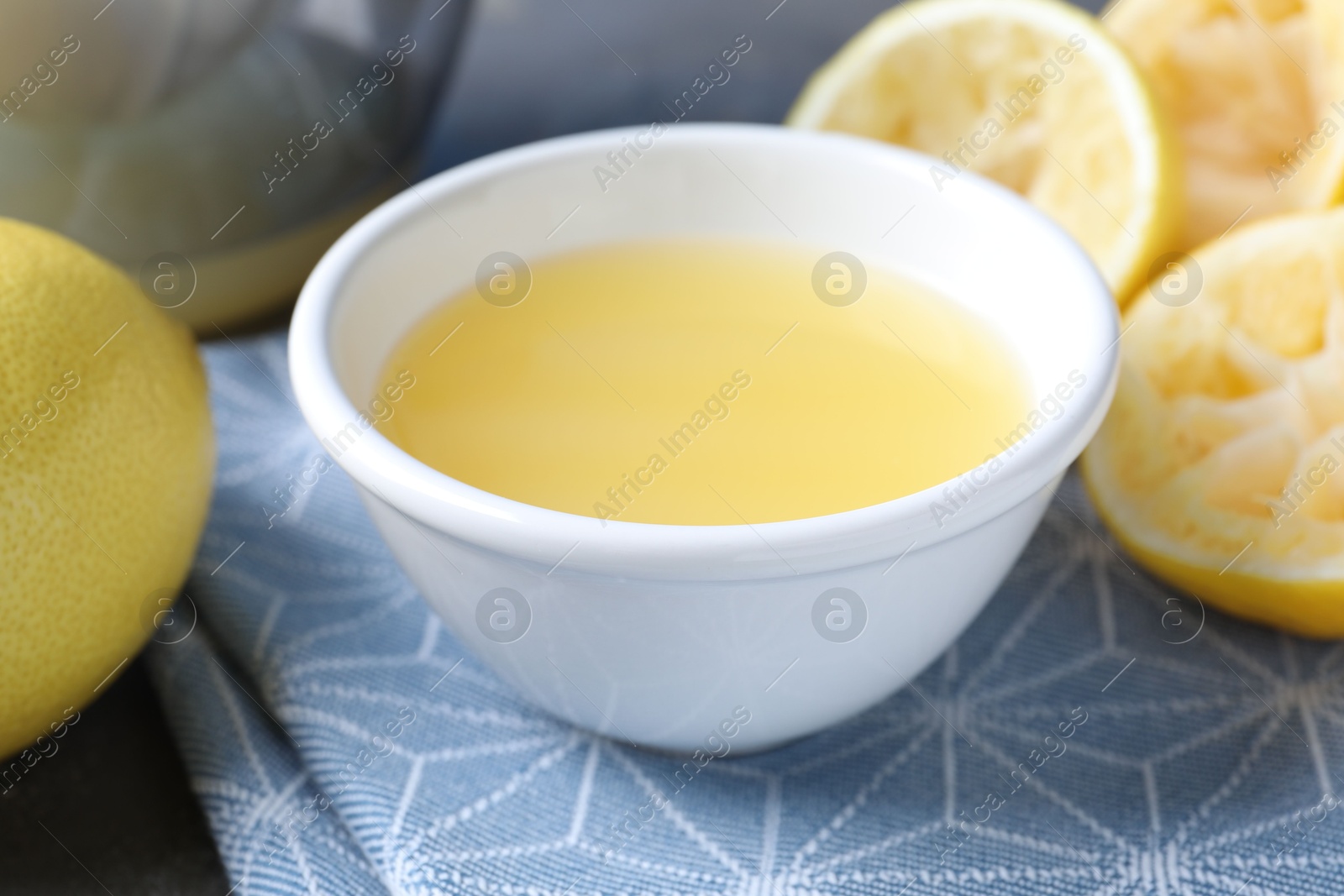 Photo of Fresh lemon juice in bowl and fruits on table, closeup