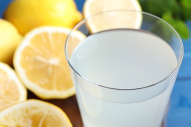 Photo of Fresh juice in glass and lemons on table, closeup