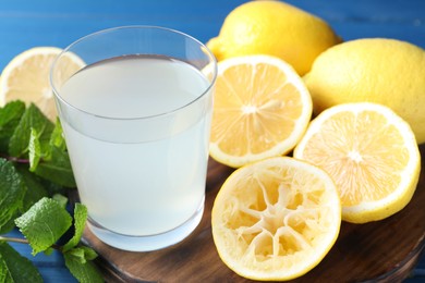 Photo of Fresh juice in glass, lemons and mint on table, closeup