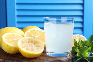 Photo of Fresh juice in glass, lemons and mint on table, closeup