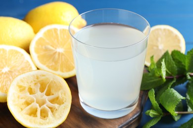 Photo of Fresh juice in glass, lemons and mint on table, closeup