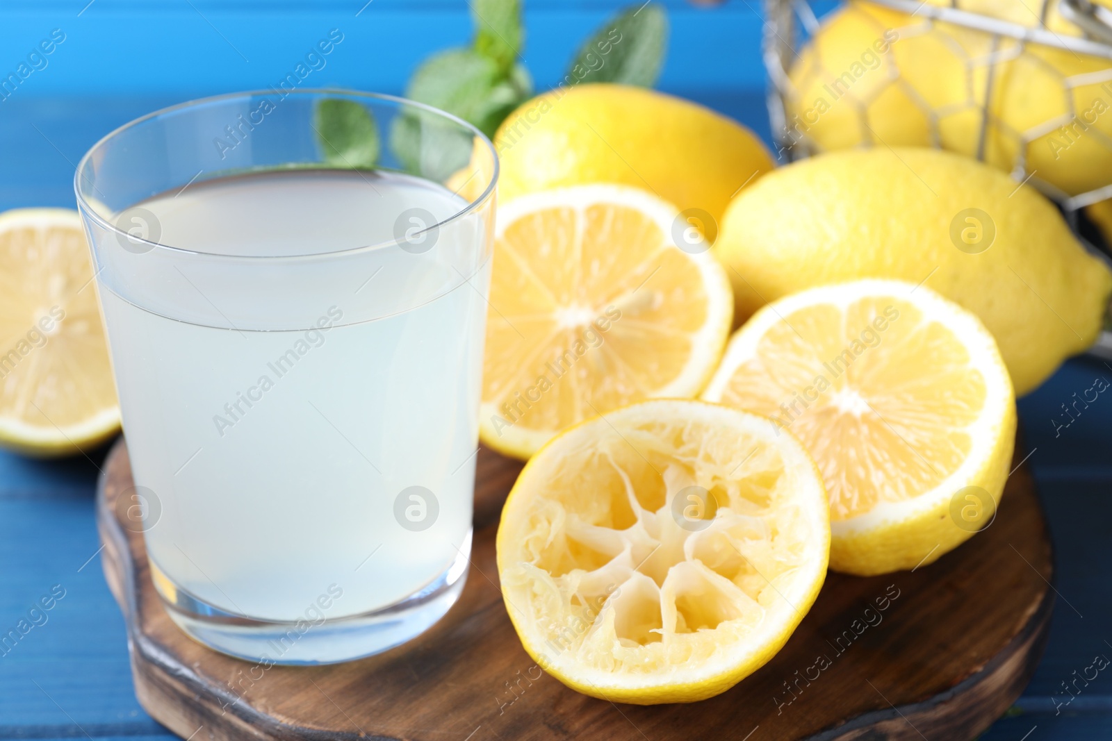 Photo of Fresh juice in glass and lemons on table, closeup