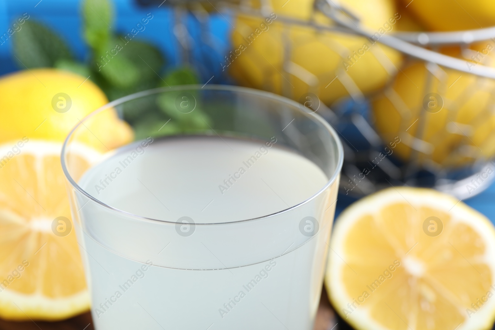 Photo of Fresh juice in glass and lemons on table, closeup