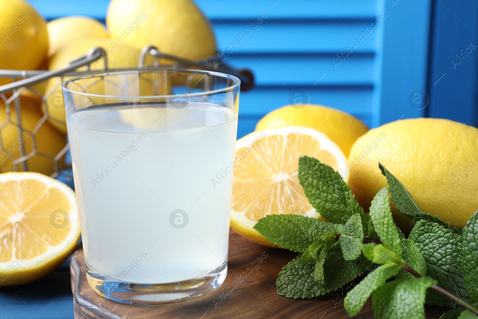 Photo of Fresh juice in glass, lemons and mint on table, closeup