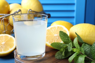 Photo of Fresh juice in glass, lemons and mint on table, closeup